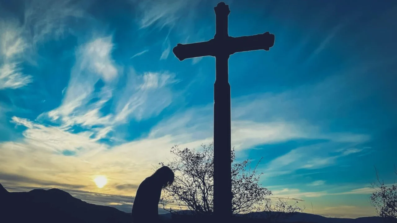 person kneeling beneath a cross asking for forgiveness