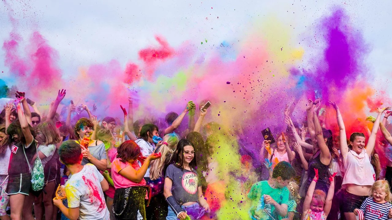 Group of people tossing colored chalk up in the air and on each other