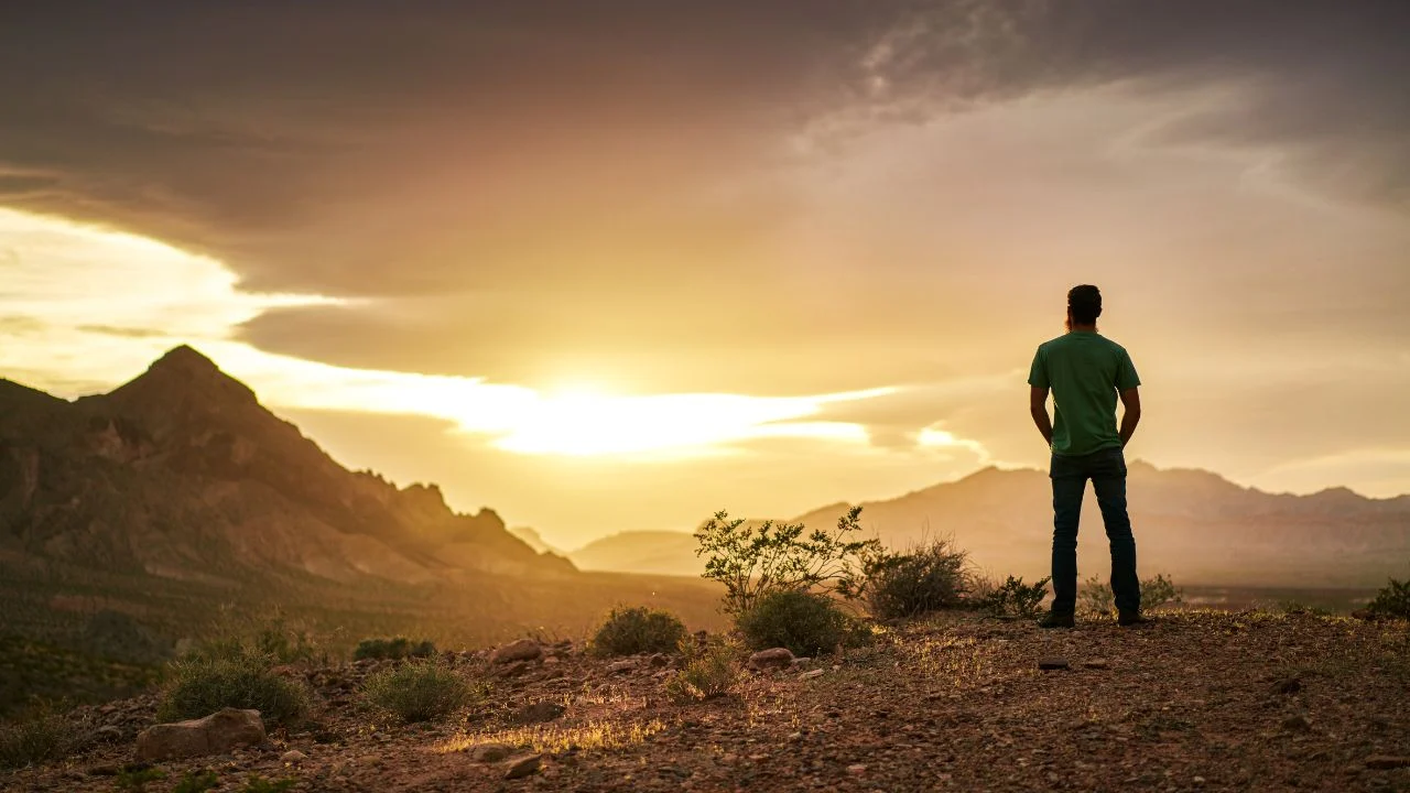 Man looking at a far away mountain at sunset