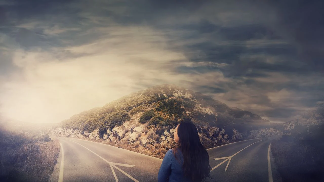 Woman standing at a fork in the road. One direction leads to darkness the other leads to the light.