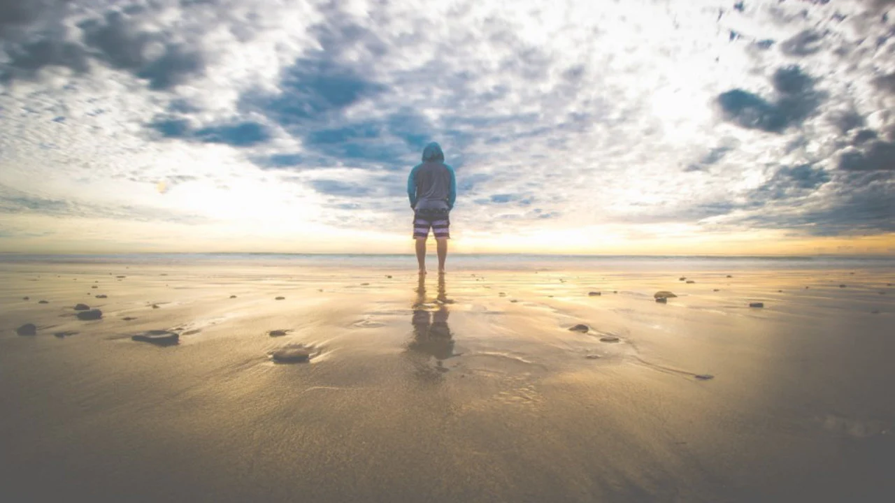 Man standing on the beach looking out at the ocean